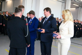 Uroczysty moment wręczania podziękowań. Na zdjęciu widoczna kobieta i mężczyźni
