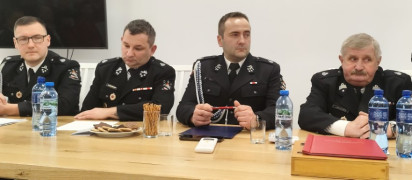 Czterech mężczyzn w mundurach strażaków. Mężczyźni siedzą przy stole 
