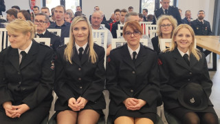 Grupa osób siedząca na krzesłach. Na pierwszym planie cztery kobiety w mundurach strażackich  
