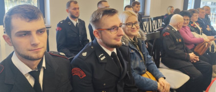 Grupa osób siedząca obok siebie na krzesłach 