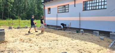Młodzi ludzie porządkują teren pod budowę garażu 