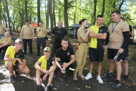 Grupa osób stoi obok siebie. Niektóre osoby siedzą