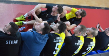 Ośmiu mężczyzn w strojach sportowych siedzi obok siebie