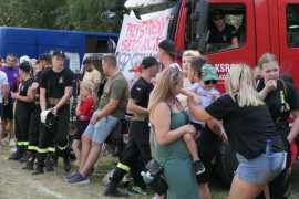Grupa osób stojąca na tle wozu strażackiego 