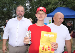 Trzy zadowolone osoby. Chłopiec trzyma w ręku dyplom i statuetkę 