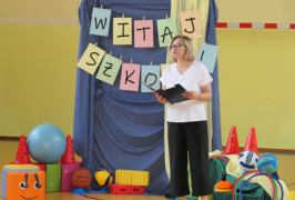 Kobieta w białej bluzce i czarnych spodniach podczas uroczystego rozpoczęcia roku szkolnego 