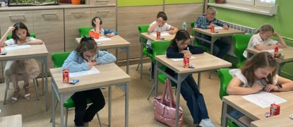Dzieci siedzą w ławkach i rozwiązują zadania 