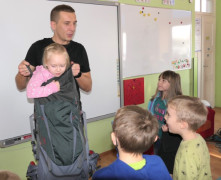 Mężczyzna i grupa dzieci. Mężczyzna trzyma dziewczynkę w plecaku 