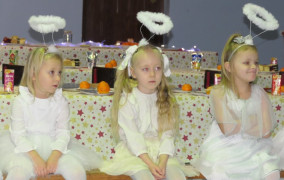 Trzy dziewczynki w białych sukienkach siedzą obok siebie 