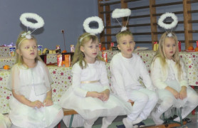 Dzieci ubrane na biało siedzą obok siebie