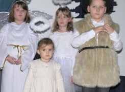 Dzieci w strojach bożonarodzeniowych stoją obok siebie 