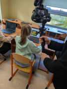 Dziewczynka siedzi na krześle. Przed dziewczynką znajduje się monitor komputera 