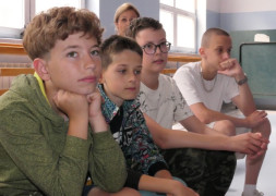 Czterej chłopcy siedzą obok siebie na ławce 
