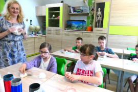 Pracownik naukowy podczas pokazywania dzieciom różnych rodzajów materiałów włókienniczych 