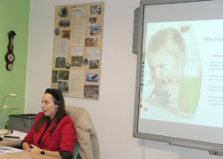 Kobieta siedzi na krześle. Prowadzi zajęcia dot. zdrowego odżywania dzieci