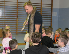 Gościem w szkole jest pasjonat gadów. Mężczyzna opowiada uczniom o nich. Dzieci mają możliwość dotknięcia węży