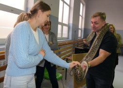 Kobieta dotyka węża, którego na szyi trzyma mężczyzna 