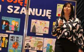 Kobieta trzyma mikrofon w ręku. Kobieta mówi do zebranych