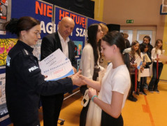 Kobieta i mężczyzna wręczają dziewczynce dyplom 