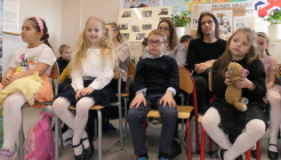 Dzieci i dorośli siedzą na krzesłach