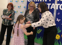 Trzy kobiety i dziewczynka. Moment wręczania dziewczynce nagrody książkowej 