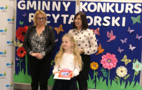 Dwie kobiety i dziewczynka. Dziewczynka trzyma w ręku nagrody książkowe 