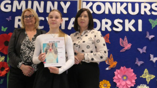 Dwie kobiety i dziewczynka. Dziewczynka trzyma w ręku dyplom 