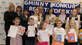 Grupa osób: dorośli i dzieci. Dzieci trzymają w dłoniach dyplomy
