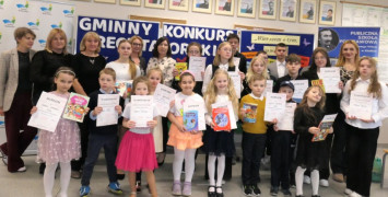 Grupa osób: dorośli i dzieci. Dzieci trzymają w dłoniach dyplomy