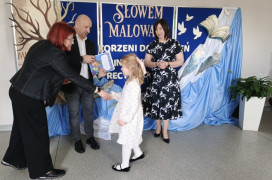 Dwie kobiety, mężczyzna i mała dziewczyna. Mężczyzna i kobieta gratulują dziewczynce 