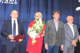 Grupa osób. Kobieta trzyma w ręku kwiaty