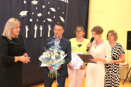 Grupa osób. Mężczyzna trzyma w ręku kwiaty
