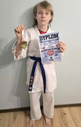 Dziewczynka trzyma w ręku dyplom i medal 