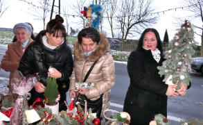 Cztery kobiety przy stoisku bożonarodzeniowym. Jedna z nich trzyma w ręku choinkę 