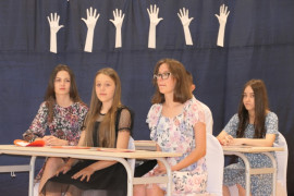 Grupa dzieci siedząca w szkolnych ławkach