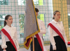 Dwie uczennice i uczeń. Uczeń trzyma sztandar szkoły. Poczet sztandarowy