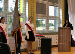 Poczet sztandarowy i kobieta mówiąca z mównicy 