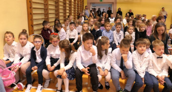 Grupa dzieci siedząca obok siebie. Uczestnicy akademii szkolnej 