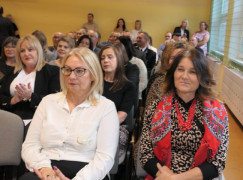 Grupa osób siedząca obok siebie na krzesłach. Uczestnicy akademii szkolnej 