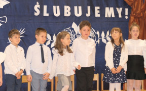 Mali uczniowie stoją obok siebie. Uczestnicy szkolnej akademii 