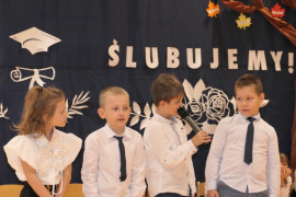 Dziewczynka i trzej chłopcy w galowych strojach. Uczestnicy szkolnej akademii 