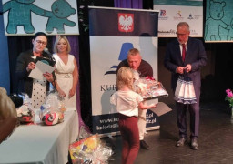 Moment wręczania nagród uczestnikom konkursu. Dorośli wręczają nagrody dzieciom 