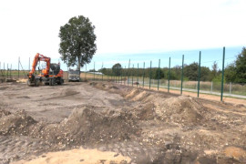 Prace remontowe na boisku. Widoczna koparka oraz  hałdy ziemi 