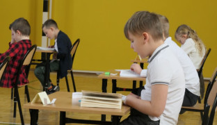 Chłopcy siedzą w ławkach i czytają fragmenty książek 
