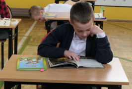 Chłopiec siedzi w ławce i czyta książkę 