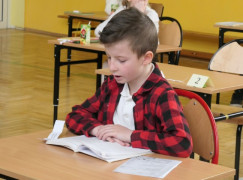 Chłopiec siedzi w ławce i czyta tekst