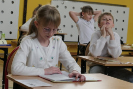 Dziewczynka siedzi w ławce i czyta książkę 