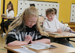 Dziewczynka siedzi w ławce i czyta książkę 