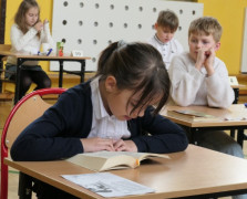 Dziewczynka siedzi w ławce i czyta książkę 