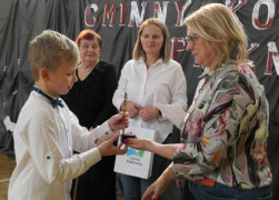 Chłopiec podczas odbierania statuetki. Statuetkę wręcza chłopcu kobieta 